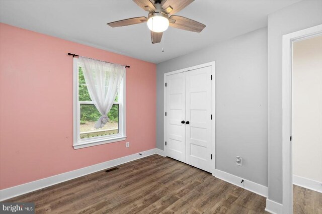 unfurnished bedroom with ceiling fan, dark hardwood / wood-style floors, and a closet