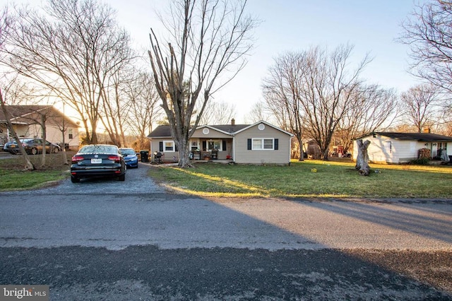 view of front of home featuring covered porch, driveway, and a front yard