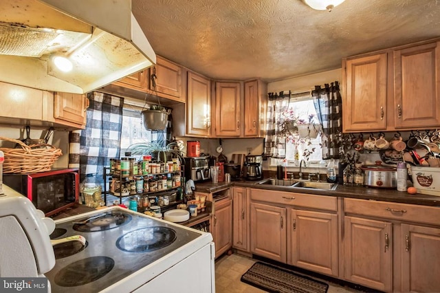 kitchen featuring a textured ceiling, a sink, electric stove, brown cabinetry, and dark countertops