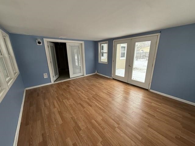 interior space with baseboards, wood finished floors, and french doors