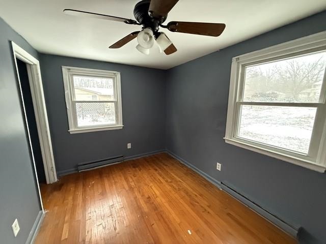 empty room featuring light wood-type flooring, a baseboard radiator, baseboards, and baseboard heating