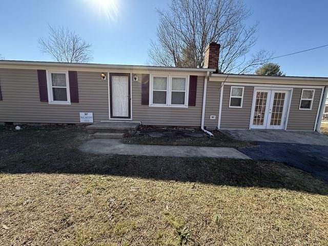 view of front of home with french doors, a chimney, and a front yard