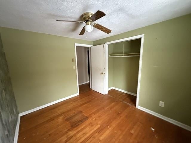 unfurnished bedroom with a textured ceiling, a closet, wood finished floors, and baseboards