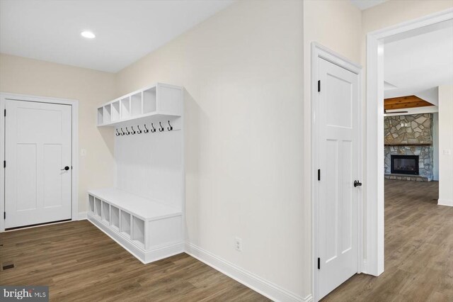 mudroom with a stone fireplace and dark wood-type flooring