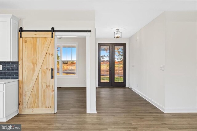 entrance foyer with dark hardwood / wood-style floors, a barn door, a chandelier, and french doors