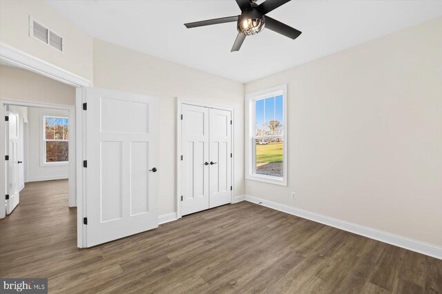 unfurnished bedroom featuring ceiling fan, dark hardwood / wood-style flooring, and a closet