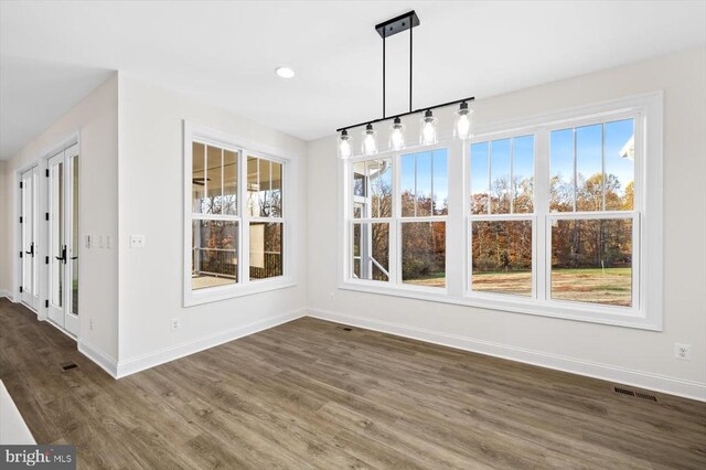 unfurnished dining area with dark wood-type flooring