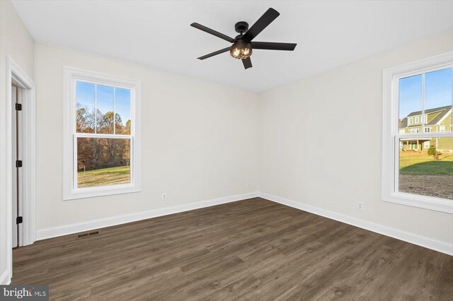 empty room with ceiling fan, dark hardwood / wood-style flooring, and a wealth of natural light