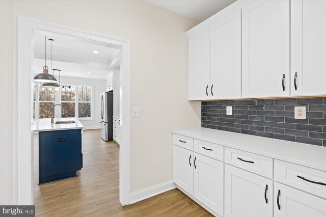 kitchen featuring stainless steel refrigerator, decorative light fixtures, white cabinetry, sink, and decorative backsplash