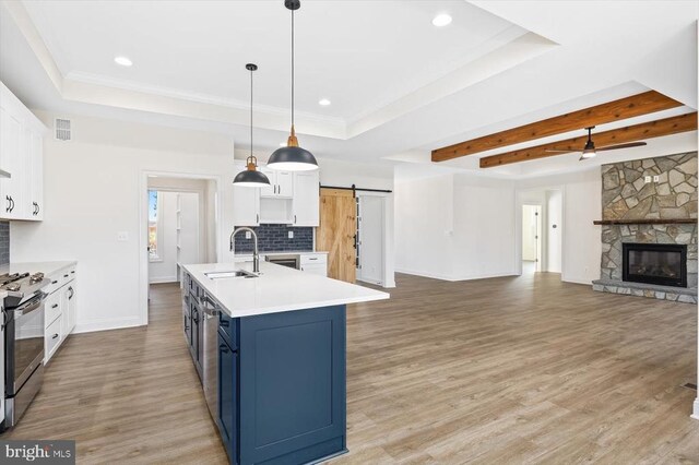 kitchen featuring sink, blue cabinetry, white cabinetry, decorative light fixtures, and a barn door