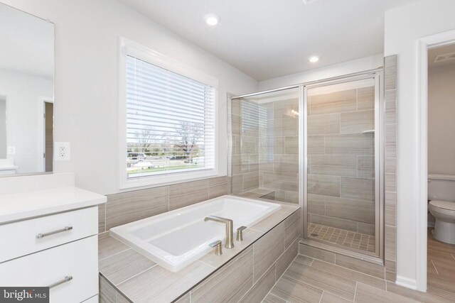 full bathroom with vanity, plus walk in shower, and toilet