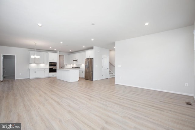 unfurnished living room featuring sink, a chandelier, and light wood-type flooring