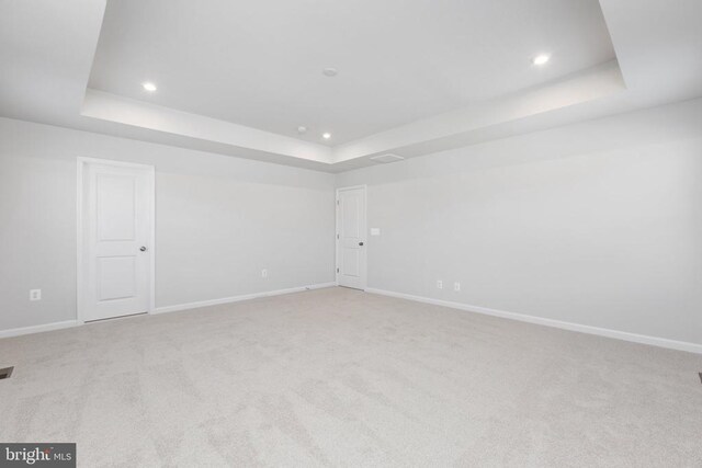 carpeted spare room with a raised ceiling