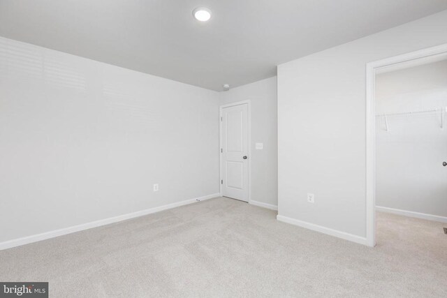 unfurnished bedroom with light carpet, a spacious closet, and a closet