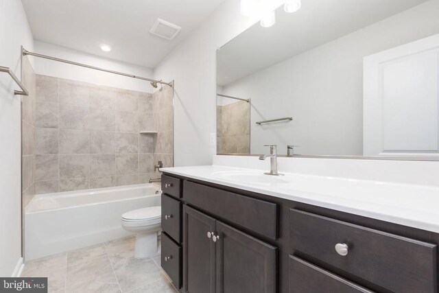 full bathroom featuring tiled shower / bath, vanity, toilet, and tile patterned floors