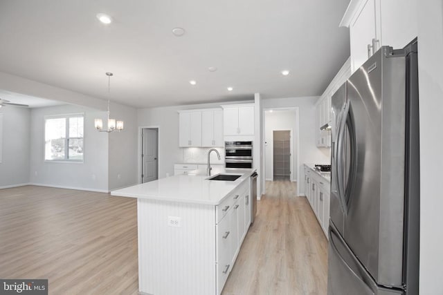 kitchen featuring sink, white cabinetry, hanging light fixtures, an island with sink, and stainless steel appliances