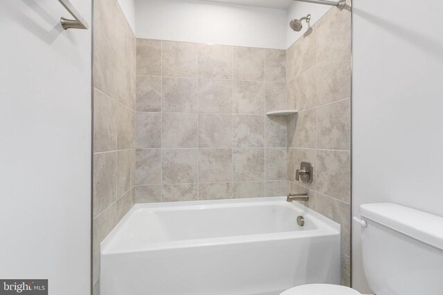 bathroom featuring tiled shower / bath combo and toilet