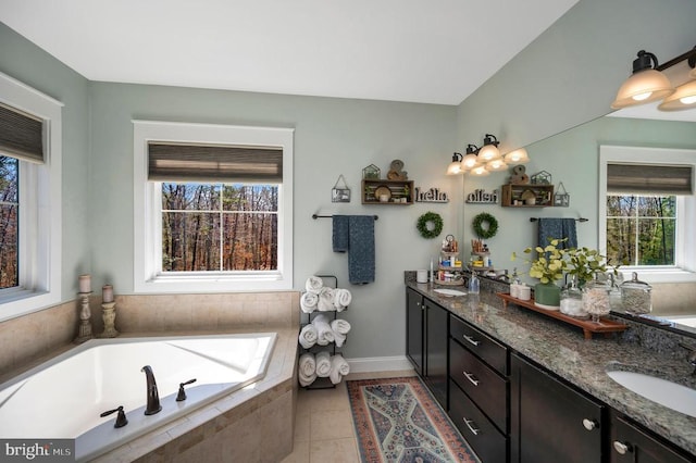 bathroom featuring a sink, double vanity, baseboards, tile patterned flooring, and a garden tub