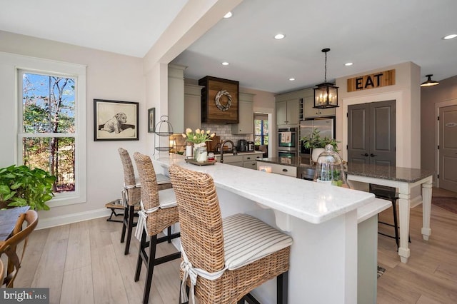 kitchen featuring baseboards, a peninsula, freestanding refrigerator, and a wealth of natural light