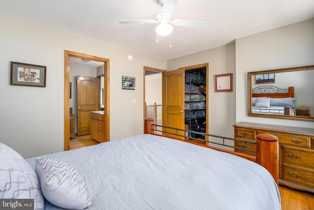 bedroom featuring ensuite bath, light wood-style flooring, a ceiling fan, and a closet