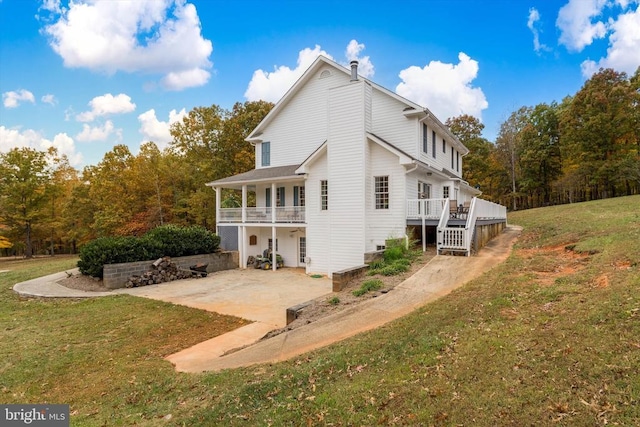 back of property featuring a deck, a lawn, and a patio