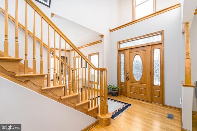 entrance foyer featuring stairs, a high ceiling, visible vents, and wood finished floors