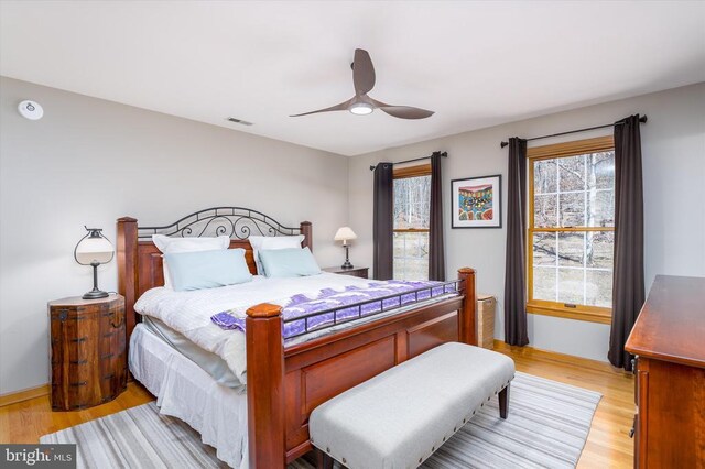 bedroom with light wood finished floors, visible vents, and a ceiling fan