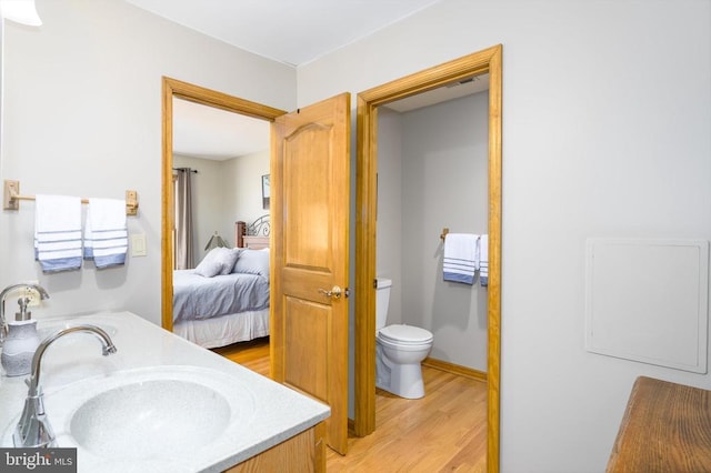 ensuite bathroom with toilet, vanity, wood finished floors, and ensuite bathroom