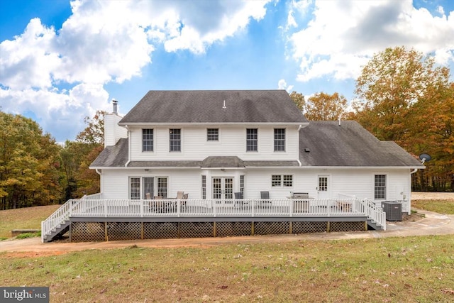 rear view of house featuring a chimney, central AC unit, a deck, and a yard