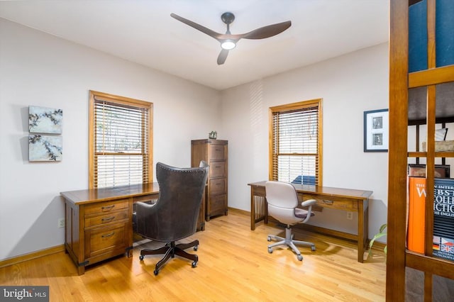 office area featuring a ceiling fan, light wood-type flooring, a healthy amount of sunlight, and baseboards