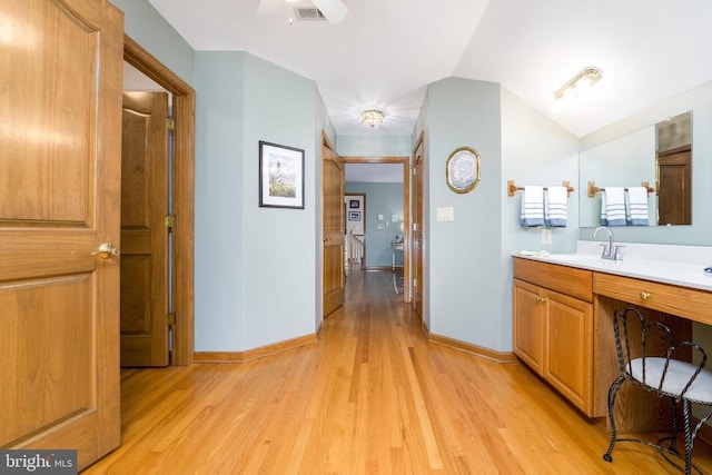 bathroom with visible vents, vaulted ceiling, baseboards, and wood finished floors