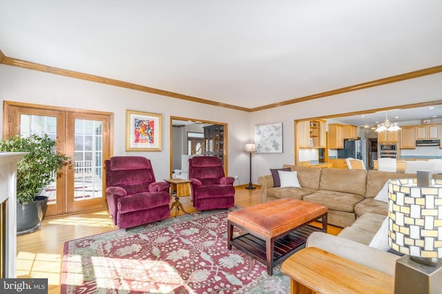 living area featuring light wood-style floors, crown molding, a notable chandelier, and french doors