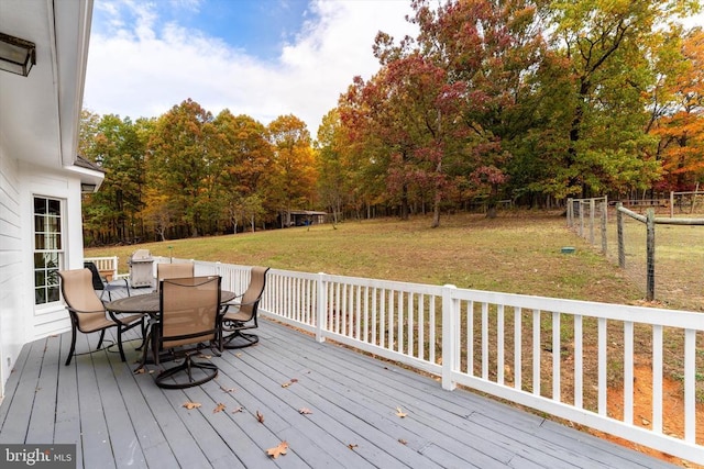 wooden terrace with fence, outdoor dining area, and a yard