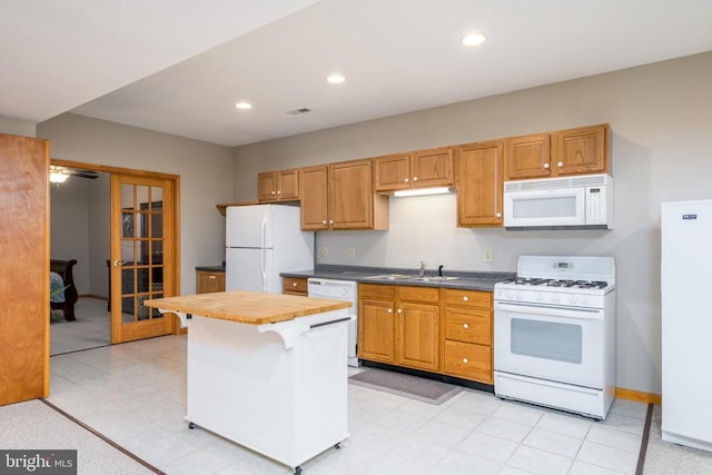 kitchen with recessed lighting, white appliances, a sink, baseboards, and french doors