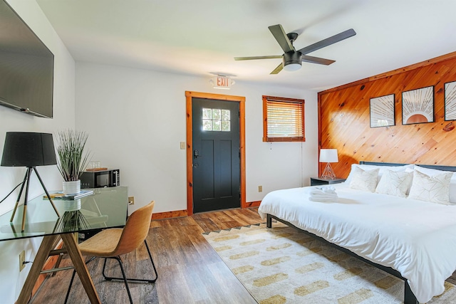 bedroom with dark hardwood / wood-style flooring and wood walls