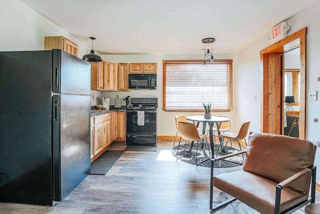 kitchen featuring dark wood-type flooring, decorative light fixtures, light brown cabinets, and black appliances