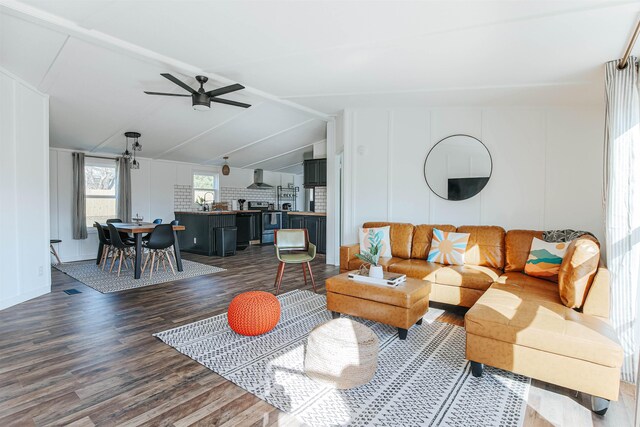 living room with dark hardwood / wood-style flooring, vaulted ceiling, and ceiling fan