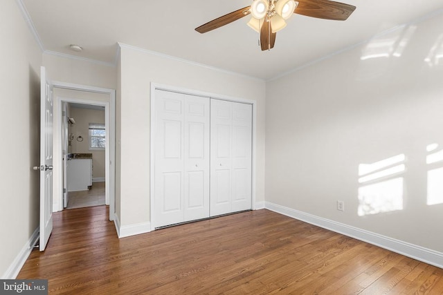 unfurnished bedroom with a closet, crown molding, baseboards, and wood finished floors