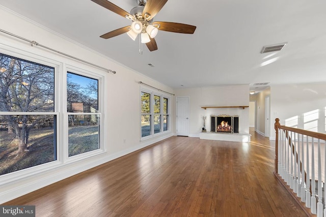 unfurnished living room with visible vents, baseboards, a lit fireplace, and wood finished floors