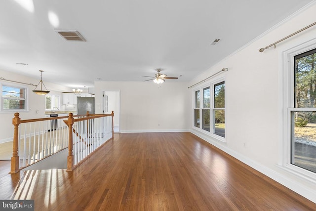 empty room featuring a wealth of natural light, visible vents, baseboards, and wood finished floors