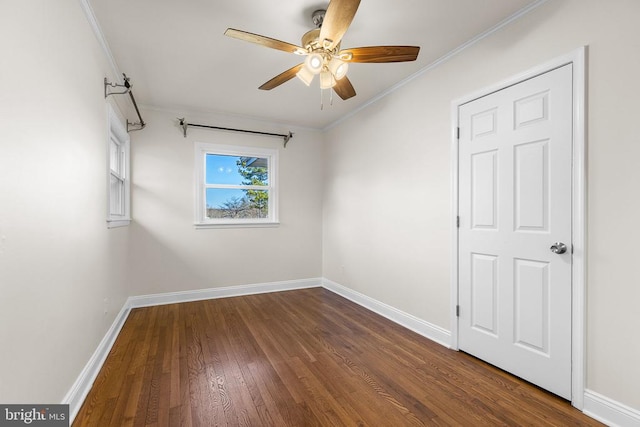 empty room featuring crown molding, wood finished floors, baseboards, and ceiling fan