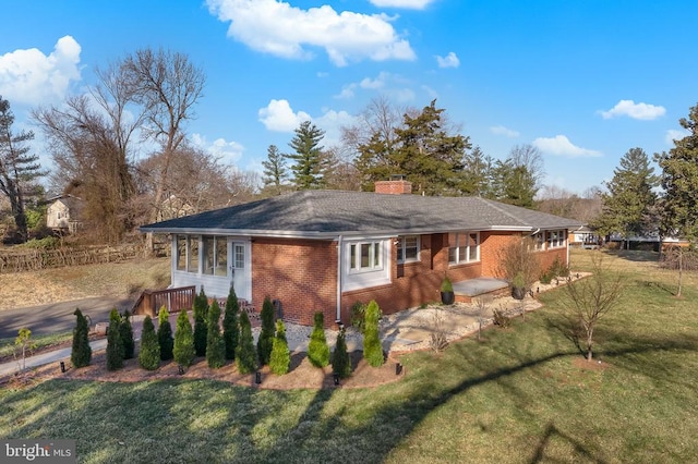 view of front of house featuring a patio, a front yard, brick siding, and a chimney