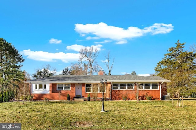 ranch-style house featuring a front yard, brick siding, central AC, and a chimney