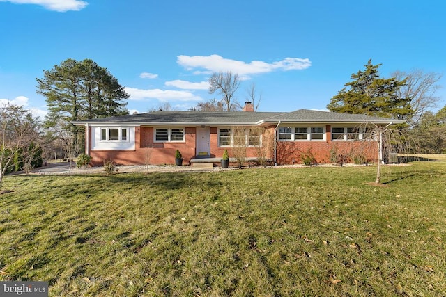 ranch-style house with brick siding, a chimney, and a front lawn