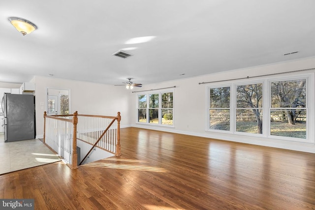 unfurnished living room featuring visible vents, light wood-style flooring, and baseboards