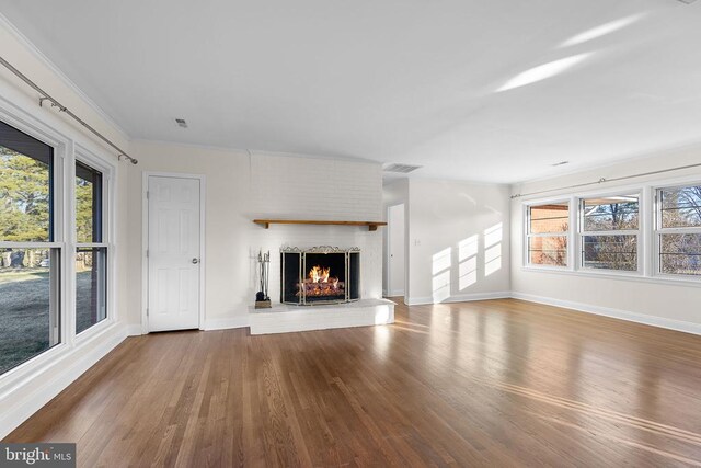 unfurnished living room featuring a brick fireplace, dark wood-type flooring, and ornamental molding