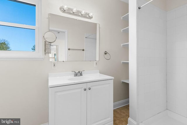 full bath with vanity, tile patterned flooring, baseboards, and a tile shower