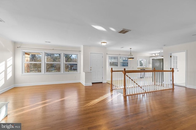 unfurnished living room featuring wood finished floors, visible vents, and baseboards