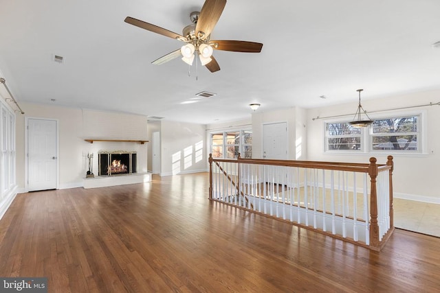 unfurnished living room featuring visible vents, baseboards, wood finished floors, and a fireplace