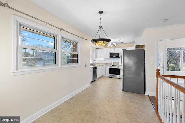 kitchen featuring a sink, backsplash, appliances with stainless steel finishes, white cabinets, and light countertops